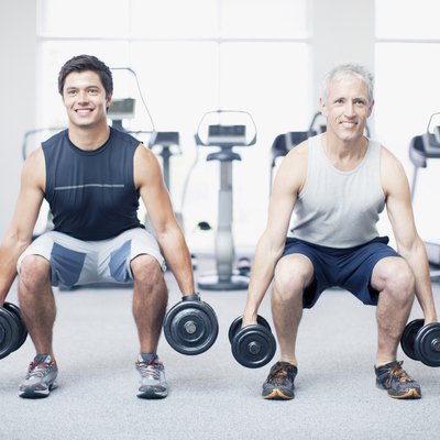 Men doing squats with dumbbells in gymnasium