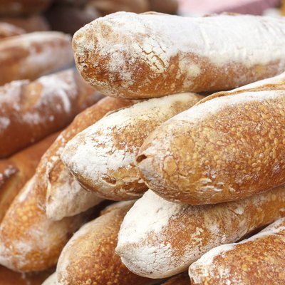 Many loaves of bread stacked in a market environment.