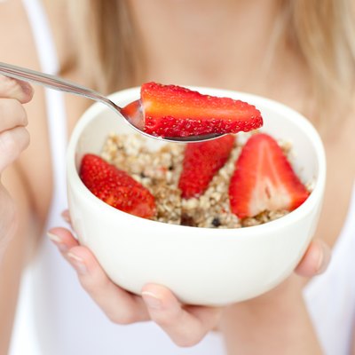 Close-up of a woman eating cereals with strawberries