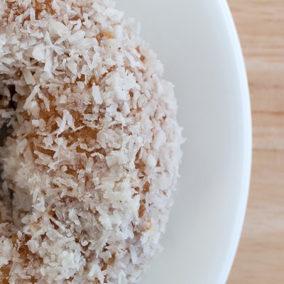 Top close view of coconut flake donut on white plate