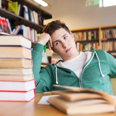 bored student or young man with books in library