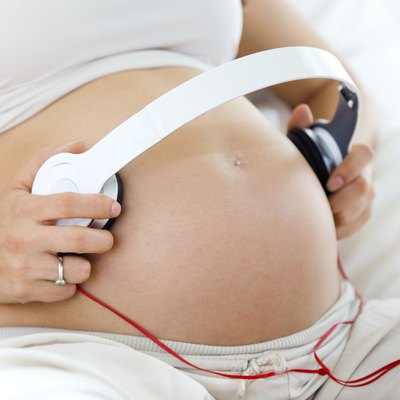 Pregnant woman putting headphones on her belly
