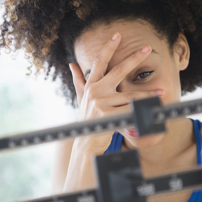 Mixed race woman hiding from weight on scale