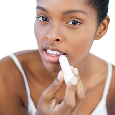 Pretty woman putting lip balm on her lips