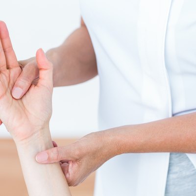 Physiotherapist examining her patients hand