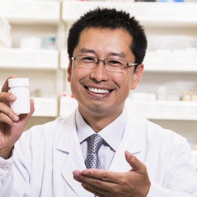 Portrait of smiling pharmacist holding a prescription medication bottle in his hand