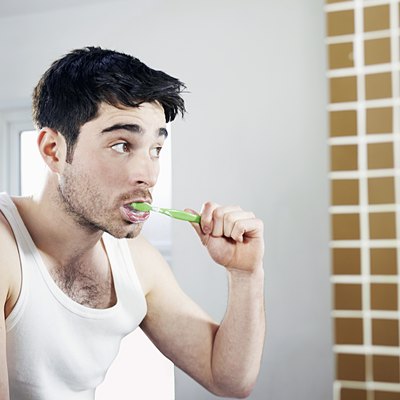man brushing teeth in bathroom