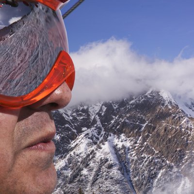 portrait of a male skier in goggles overlooking the snow covered mountains