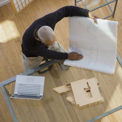 African architect looking at building model and blueprints