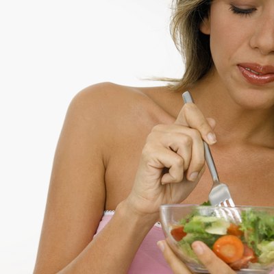Young woman holding a fork in a bowl of salad
