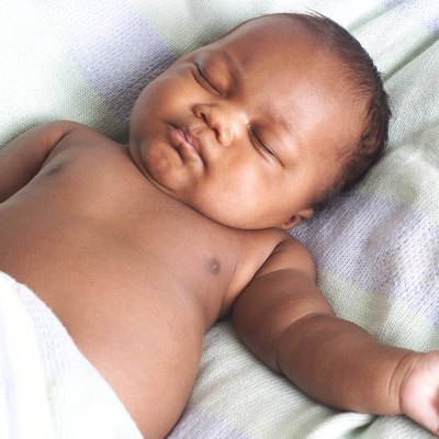 an african american baby lies on its back and sleeps peacefully