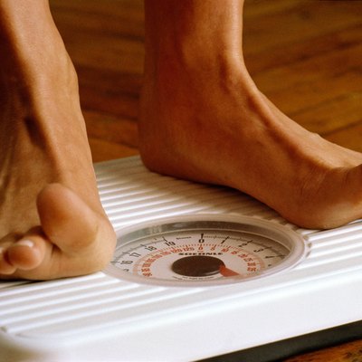 Woman weighing herself on bathroom scales,detail of feet