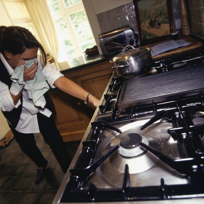 Woman checking for gas leak in cooker