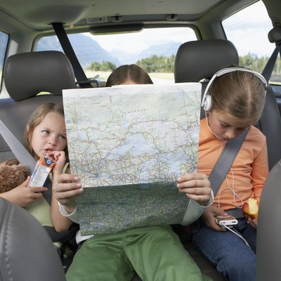 Three girls (6-8 years) sitting on rear seat of car on road trip