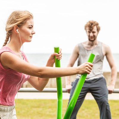 Man and woman exercising on elliptical trainer.