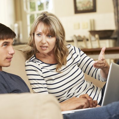 Mother And Teenage Son Arguing On Sofa