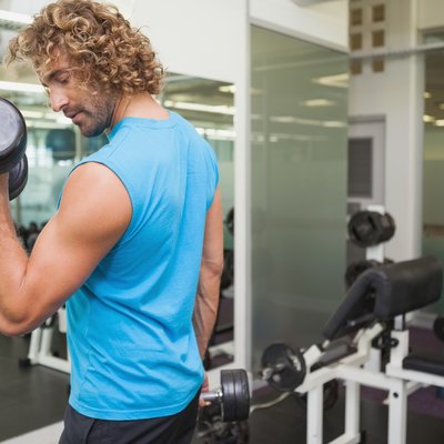 Handsome young man exercising with dumbbell in gym
