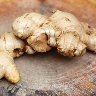 fresh ginger root on wooden chopping block.