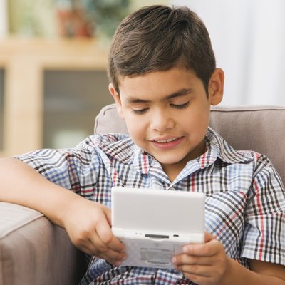 Hispanic boy playing handheld video game on sofa