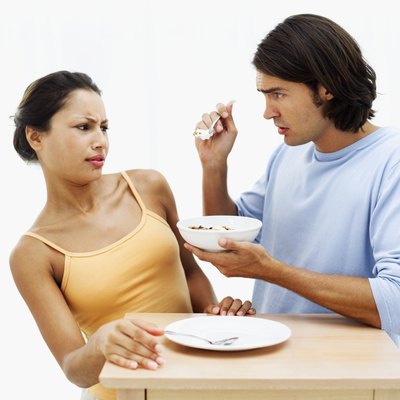 Young man offering bite from bowl to woman