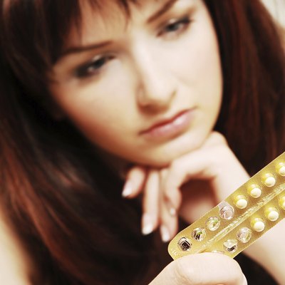 Young woman looking at her contraceptive pills