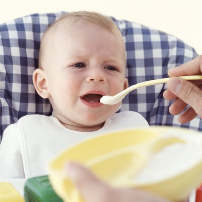 Father feeding baby (6-12 months), indoors