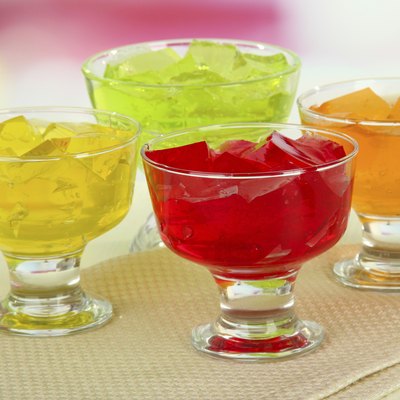 Tasty jelly cubes in bowls on table on light background