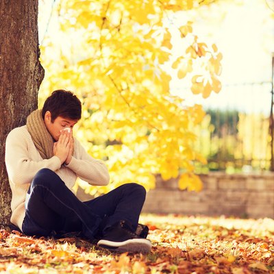 ill man with paper tissue in autumn park