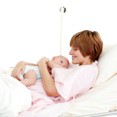 Smiling patient with newborn baby in bed