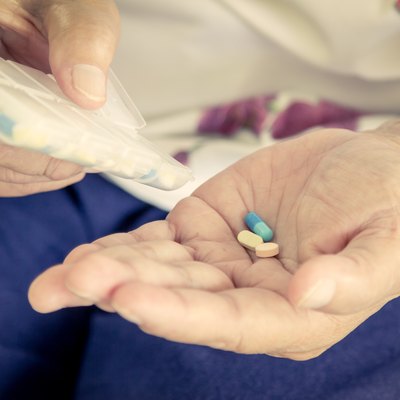 old woman hand pouring pills from a pill reminder box