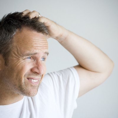 Man with bedhead trying to cover his hair with hand