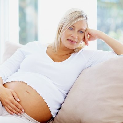 Thoughtful mature pregnant woman relaxing on couch