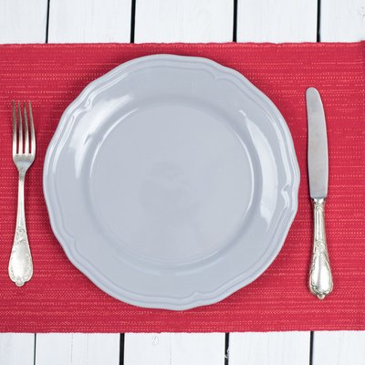 Empty Grey Plate on a red placemats with silverware