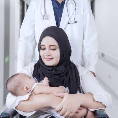 Mother with baby on wheelchair and her doctor