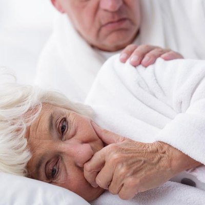 Senior woman coughing in bed