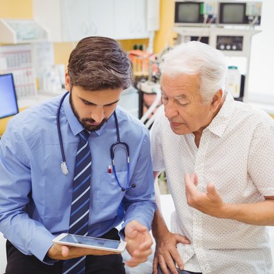 Doctor discussing with patient over digital tablet