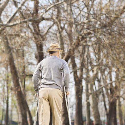 Elderly gentleman with crutches, walking in park