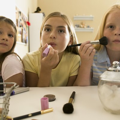 teenage lifestyle shot of three female friends as they sit at a vanity and put on make up