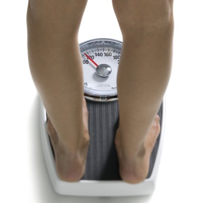conceptual shot of the legs of a young adult woman as she stands on a bathroom scale