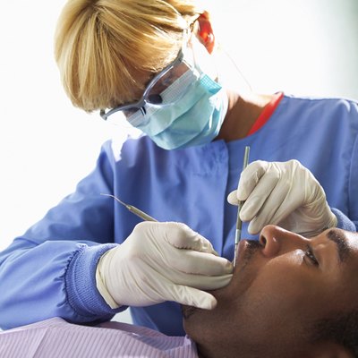 A dental hygienist works on a patient's mouth during a dental exam