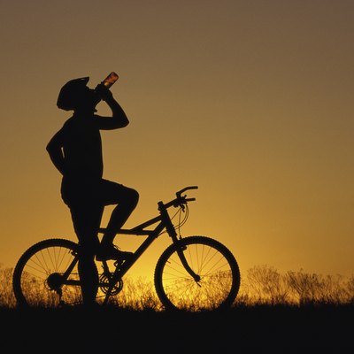 Silhouette of a man drinking water on a bicycle