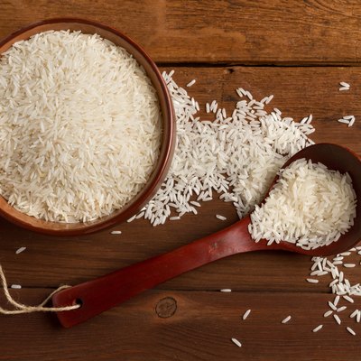 Rice in ceramic bowl and spoon on a wooden table