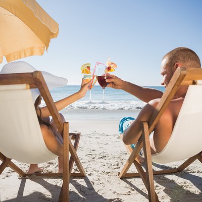 Happy couple clinking their glasses while relaxing on their deck chairs