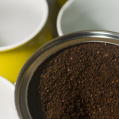 can of ground coffee beans with mugs