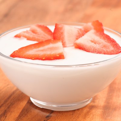 full bowl of yogurt with strawberries on wood