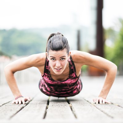 Young Woman Exercising Push-Ups on Wooden Floor.
