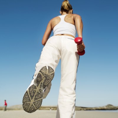low angle view of a woman working out with dumbbells on the beach