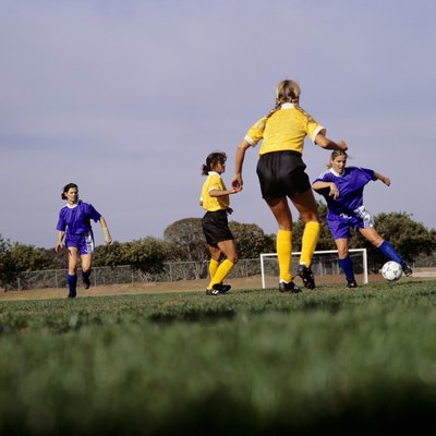 Young women playing football on grass pitch, surface view
