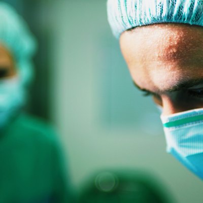 "Operating theatre team at work, surgeons with sweaty brow, close-up"