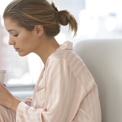 Young woman on sofa, looking at cup, close-up, profile